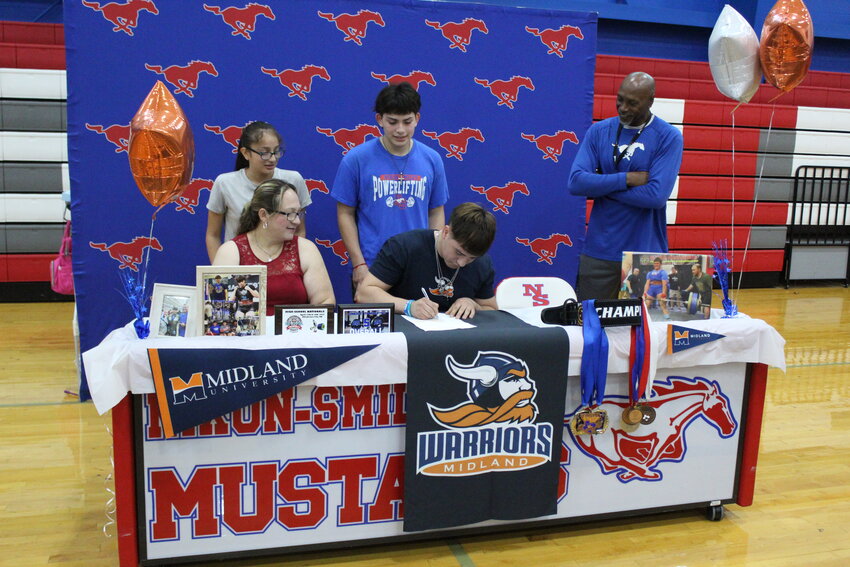 Mustangs senior powerlifter Jesus Espino signs his letter to Midland University in Fremont, Neb. Monday, April 29 in the Nixon-Smiley High School gym.
