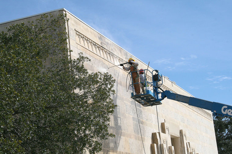 Workers remove discoloration that has tarnished the exterior of the Memorial Museum for decades. The process will take about a month, city officials said.