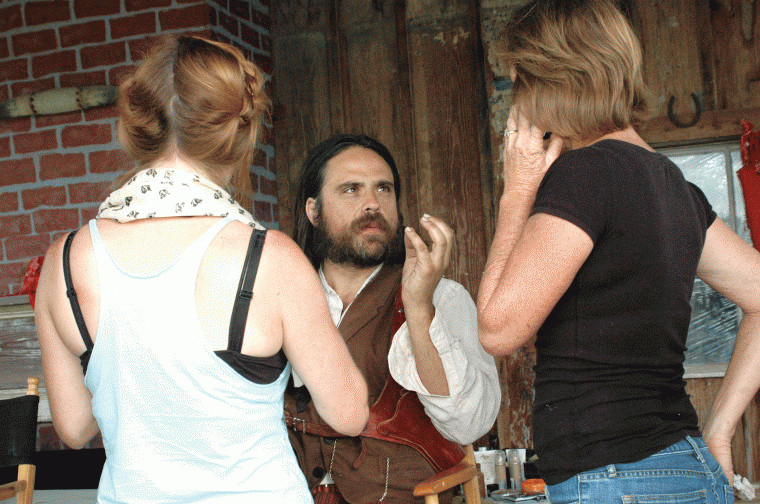 April Swartz (left) prepares to apply makeup while Justin Meeks talks with Cindy Munson, manager at the Pioneer Village Living History Center in Gonzales, Texas.