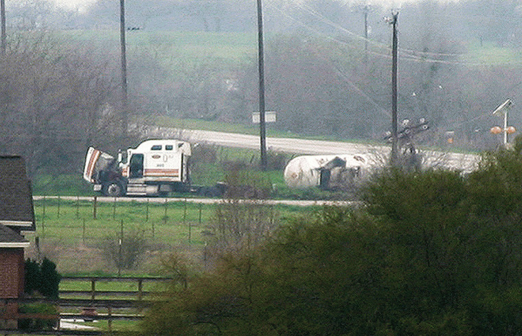 A zoom lens used from a safe distance captures the overturned
trailer and the disabled tractor at the intersection of state
Highway 97 and FM 108. Homes within a mile radius of the accident
were evacuated as a precaution after propane began spilling at the
accident site.