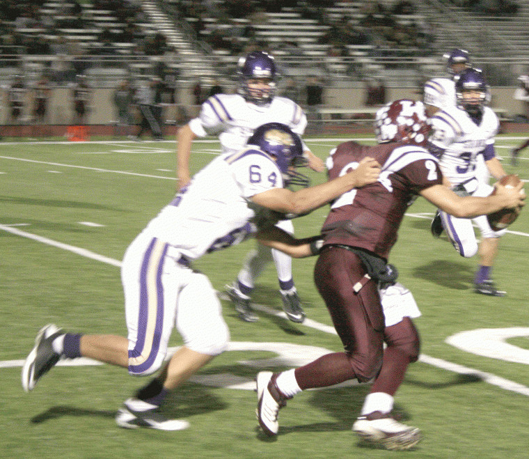 Shiner defender Max Huth (64) gets his hands on Kenedy
quarterback Rollie Zepeda during the Comanches’ 35-6 victory over
the Lions in the bi-district round of the Division I-Class A state
playoffs Nov. 10 in Floresville.