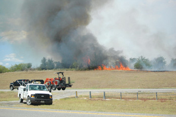 Above, after expending all the water aboard Engine 37, Gonzales
firefighters watch helplessly as a huge pile of railroad timbers
are engulfed by fire Tuesday afternoon. Two blazes off Harwood Road
in northern Gonzales County were preceded by a firestorm along I-10
(far left and right) that charred more than 60 acres and threatened
the home of a invalid man who had to be rescued by
firefighters.