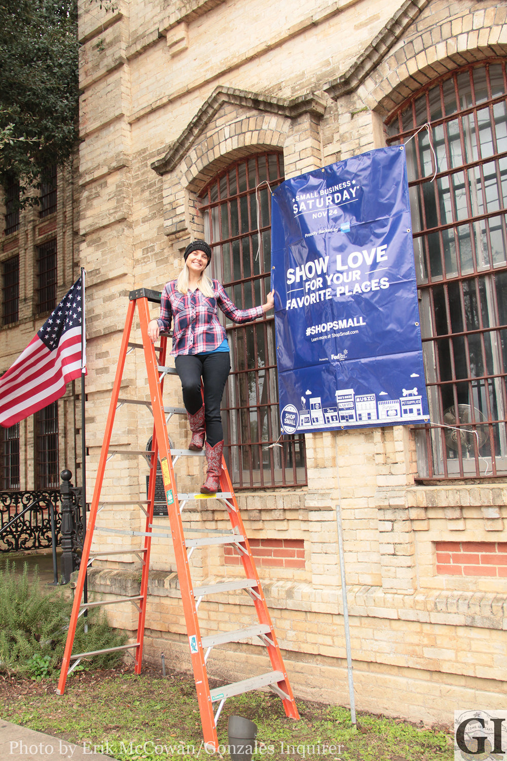 Gonzales Chamber of Commerce Executive Director Daisy Scheske Freeman wants to let the town know that Small Business Saturday is coming up next week. Here, she hangs a banner off of her offices at the Old Jail.