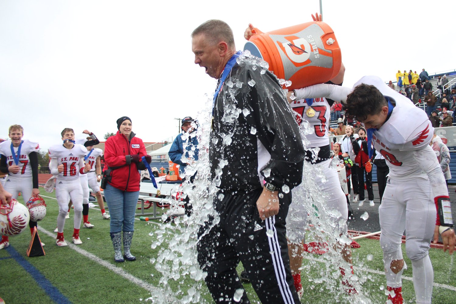 Shiner St. Paul Head Coach Jake Wachsmuth receives the celebratory cooler bath after his fifth state title win.