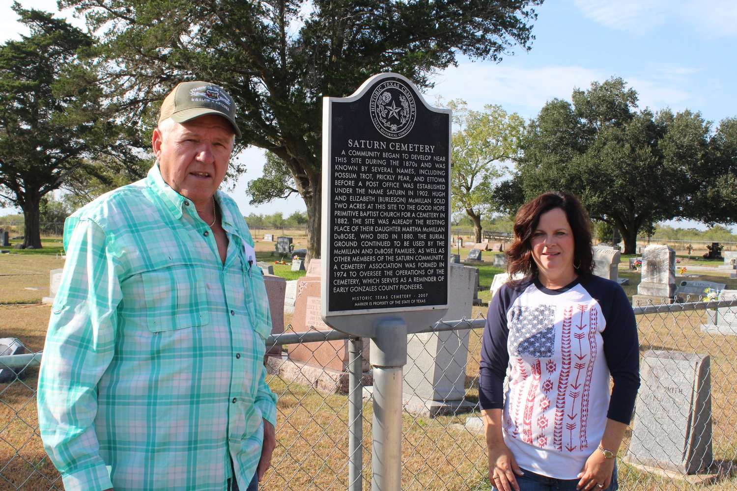 Joe Solansky (left) and Melissa Clampit stand in front of the Saturn Cemetery Historic Register marker while work is being done to clean up and restore the grave sites of 93 veterans interred in the ceremony.