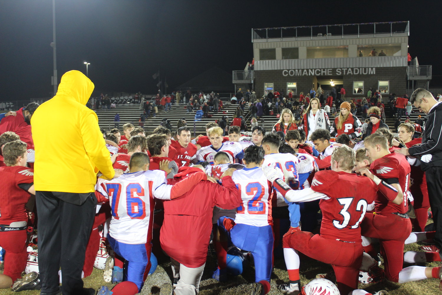 Players from both Shiner St. Paul and San Antonio St. Gerard kneel for prayer after Friday’s game at Comanche Stadium. The Cardinals came away with a 42-14 win.