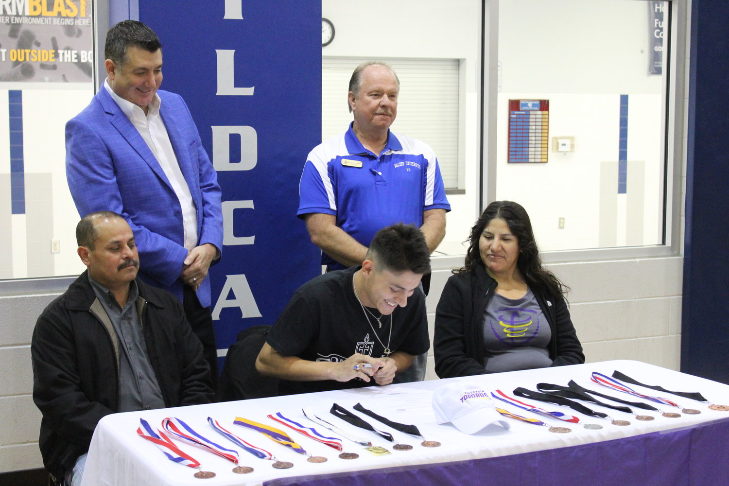 Miguel Morales, surrounded by parents and Waelder ISD administrators, signs his letter of intent to run for Concordia University Texas.