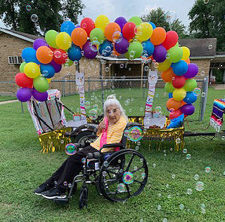Maria De Jesus “Jesusa” Almaraz poses in front of one of the parade floats Monday in honor of her 103rd birthday.