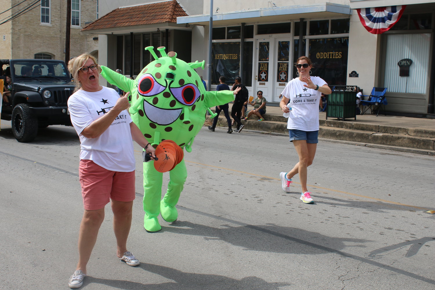 Gonzales Healthcare Systems executive director Kelly Lindner runs away from a very scary COVID-19 monster before turning around to bat it with a GHS giveaway fan during the annual Come and Take It Celebration parade on St. Paul Street Saturday morning. GHS will have their annual Drive-Thru Flu Shot Clinic this Thursday, Oct. 7, in Gonzales and Friday, Oct. 15 in Nixon.