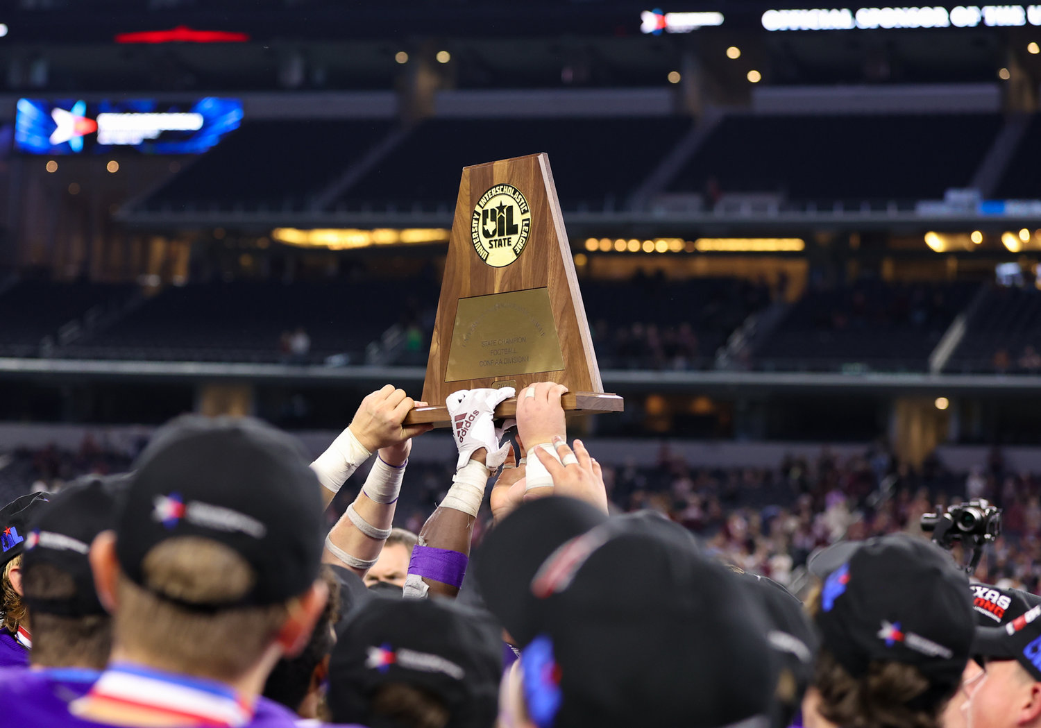 The Shiner Comanches hold up the Class 2A Division I state championship trophy after a 47-12 win over Hawley on December 15, 2021 in Arlington, Texas.