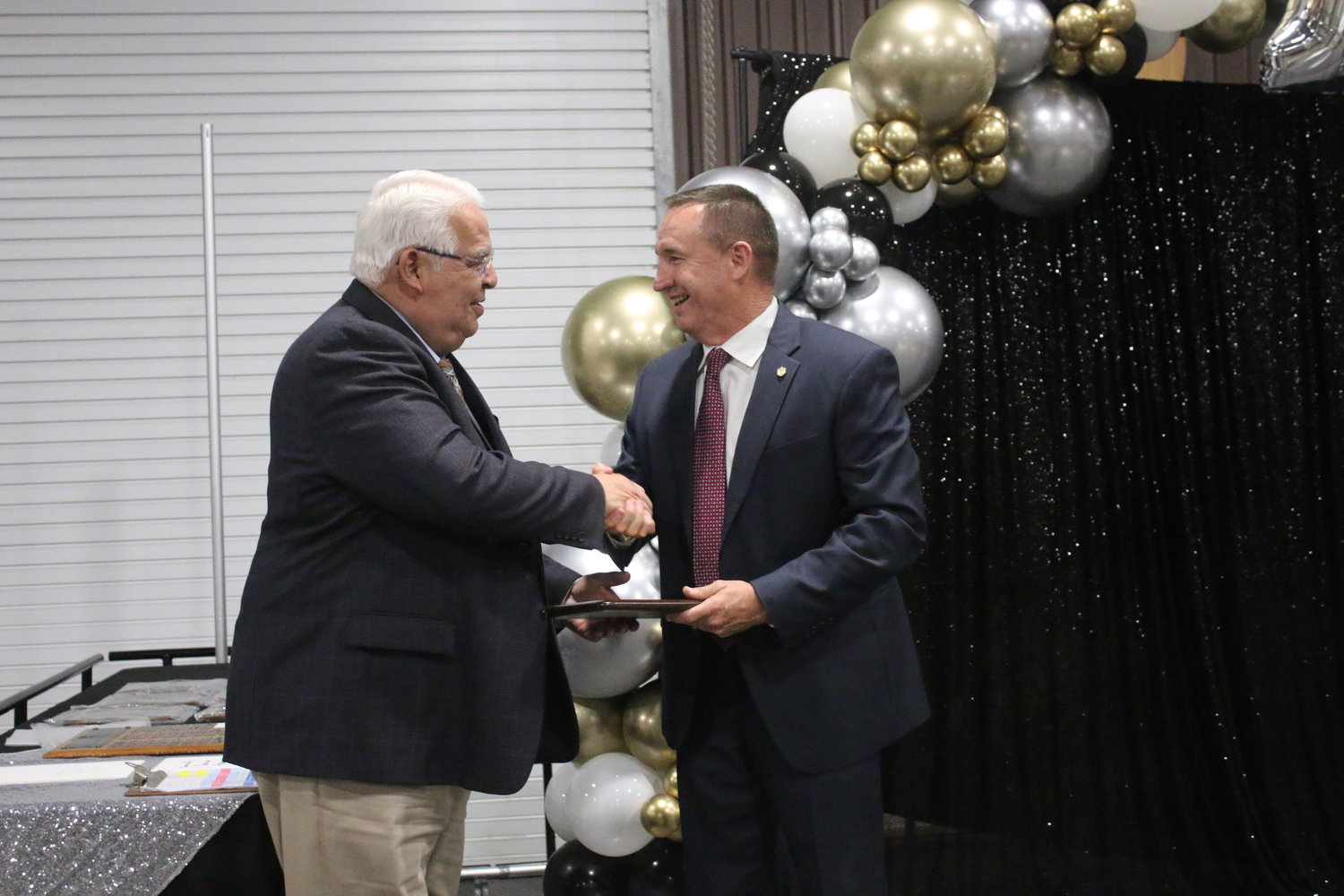 Andy Rodriguez, left, is congratulated by County Judge Patrick Davis for winning the David B. Walshak Lifetime Achievement Award from the Gonzales Chamber of Commerce & Agriculture at their 100th banquet Thursday, April 7, at JB Wells Expo Center.