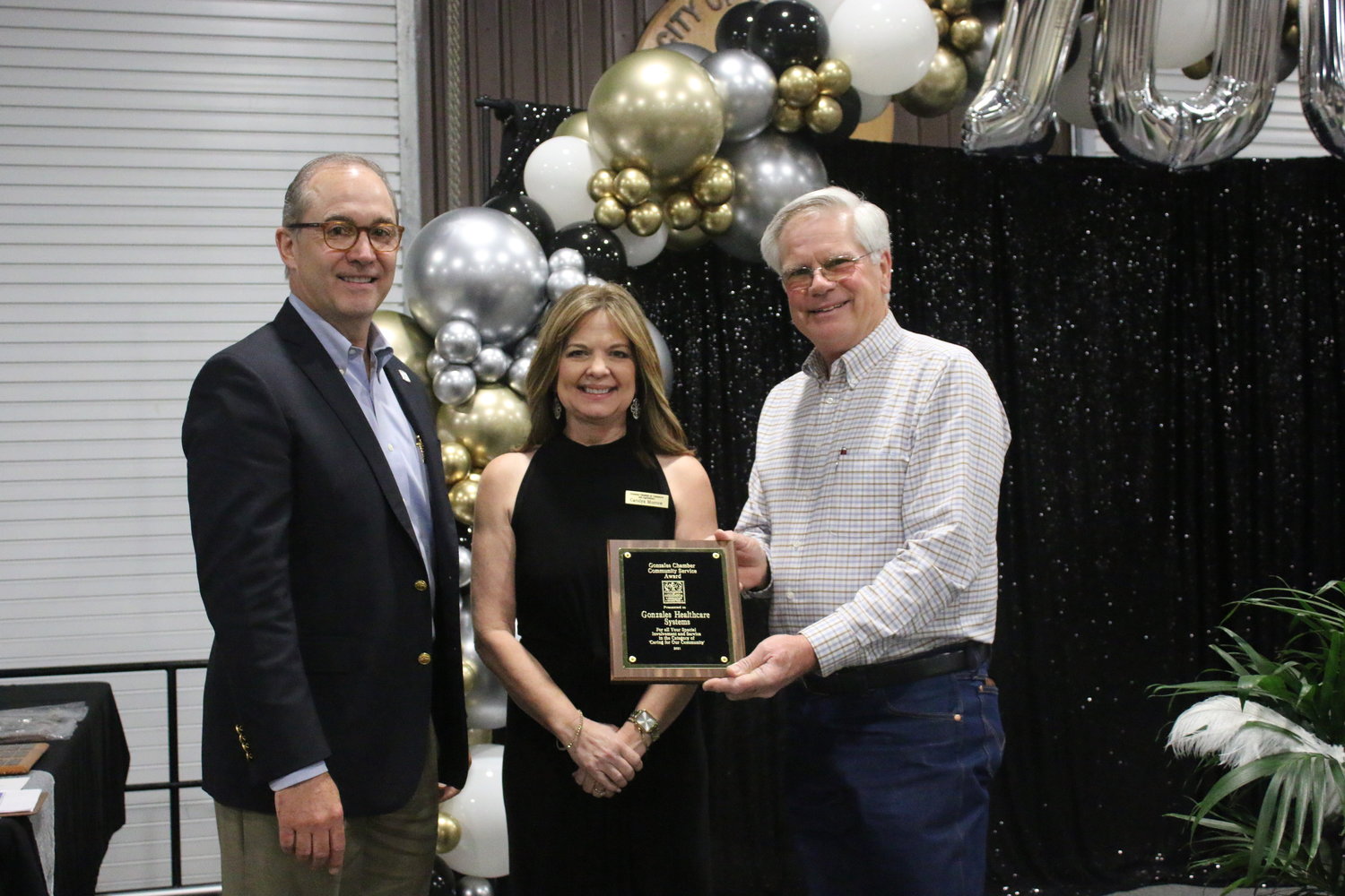 Gonzales Chamber of Commerce & Agriculture incoming president Carolyn Morrow, center, presents the Community Service Award to Dr. Commie Hisey, left, and Kenneth Gottwald, board president, of Gonzales Healthcare Systems at Thursday’s banquet. The hospital system was recognized for taking the lead in helping the community get vaccines to fight COVID-19.