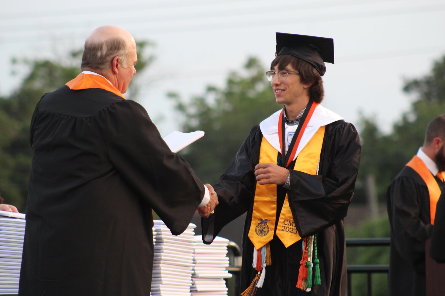 Valedictorian Cooper LaBuhn shakes hands with school board president Ross Hendershot, III and hand’s LaBuhn his diploma.