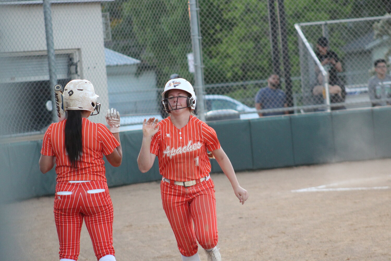Lady Apaches pitcher Haley Cantu (4) high fives freshman catcher Blakely Mercer (1) for scoring a run against JFK Thursday, March 28