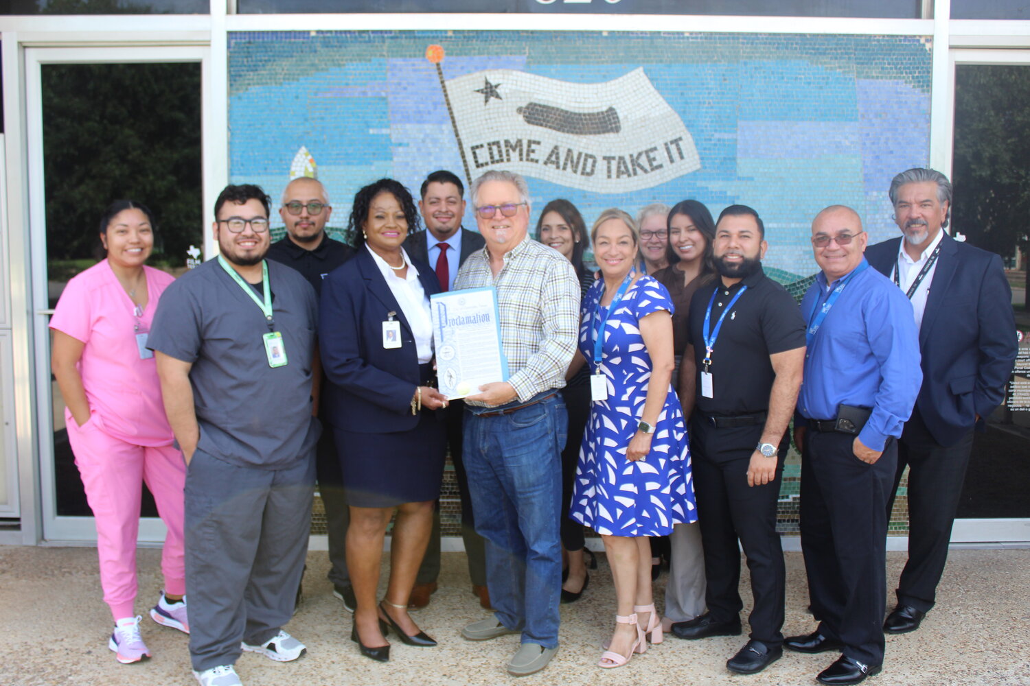 Community Health Centers of South Central Texas staff are pictured with Mayor Sucher of Gonzales, Texas, officially proclaiming National Health Center Week from Au. 4-10. The photograph captures this significant moment, showing Mayor Sucher making the declaration, symbolizing the support and recognition of Community Health Centers.