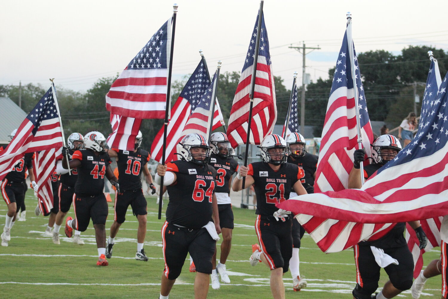 The Gonzales Apaches run onto the field of Apache Stadium with American flags for law enforcement and military appreciation Friday, Sept. 20.