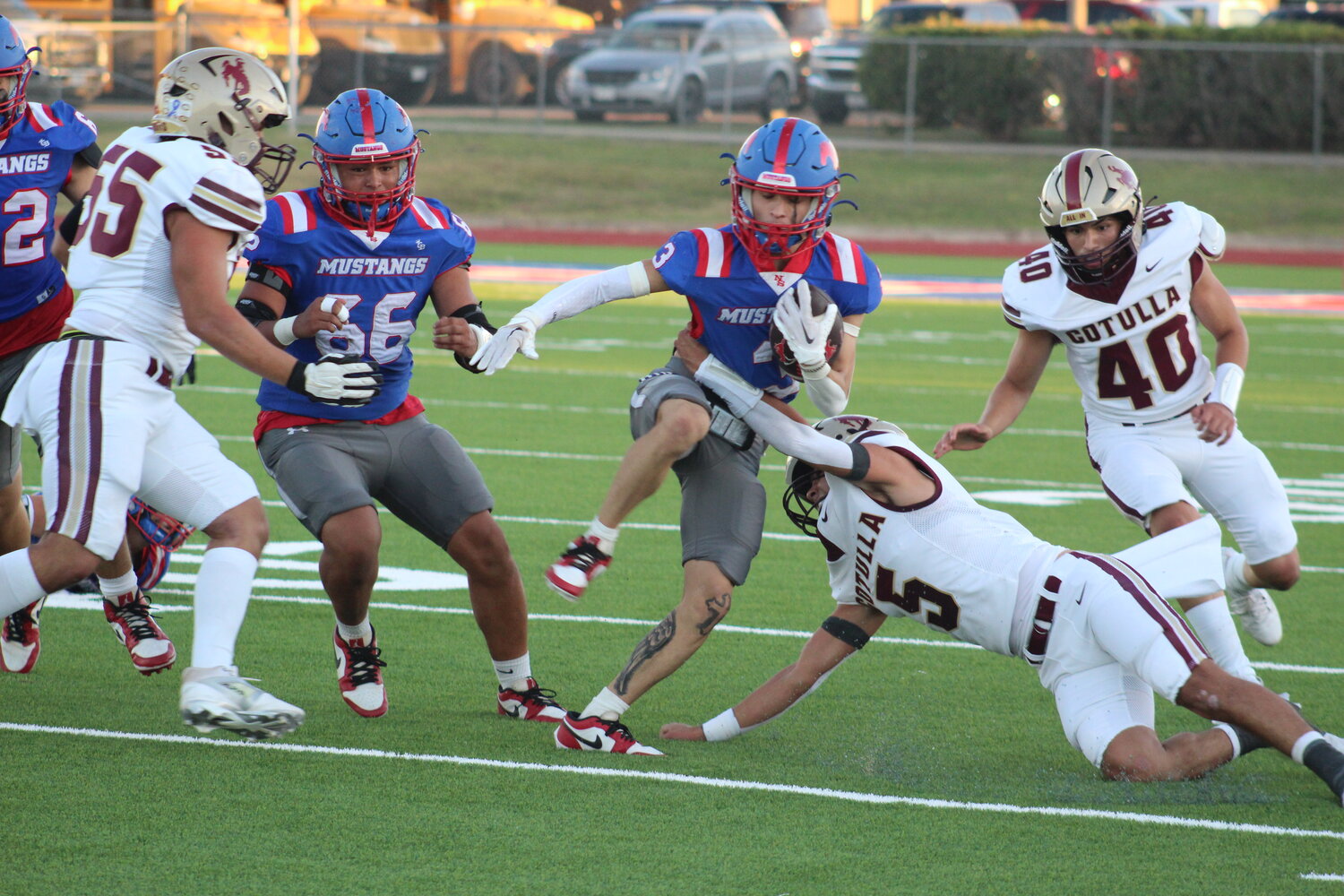 Mustangs senior running back Aiden Flores moves pass three Cowboys defenders in the district opener. Flores carried the ball for 38 yards and one touchdown in the, 18-11, loss to Cotulla.