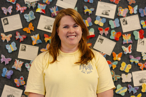 Daphne High School Social Studies Department Chairperson Kat Robinson standing in front of the wall of ceramic butterflies. / Natalie Williamson