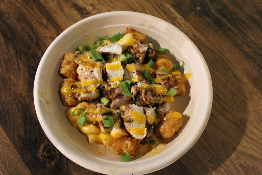 The grilled chicken bowl is loaded with beer cheese mac and cheese, tots and topped with Tang aioli and green onions.