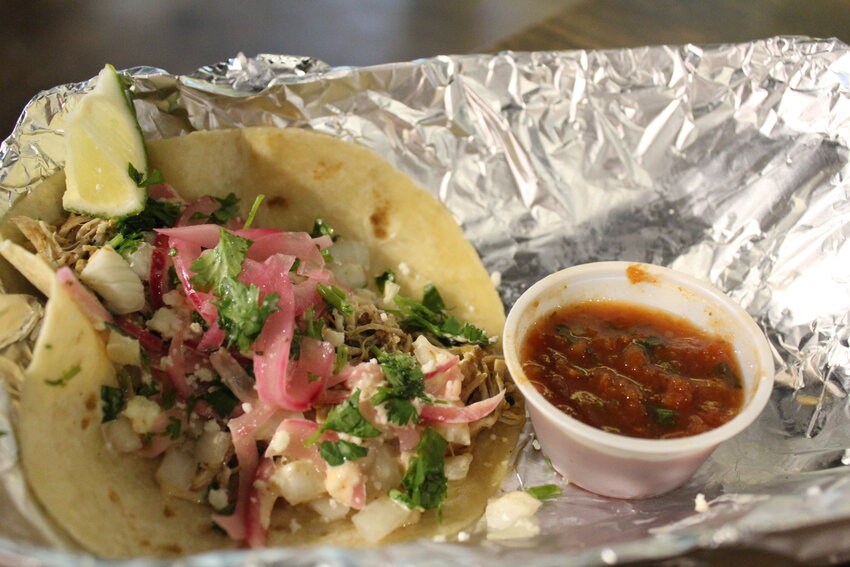 The fire-roasted chicken street taco topped with cilantro, pickled onions, queso fresco, sauce Hermanos and a lime wedge.