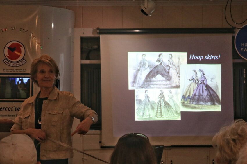 Dolores Hydock shows the size of a typical hoop skirt by using a measuring tape and a participating audience member.