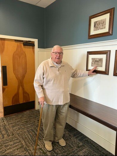 Rev. Albert Kennington shows a photograph hanging in the Alves Building at Beckwith Lodge and Conference Center. The mule in the photograph was brought to the camp by Chief Fred Walker of the Poarch Creek Indian tribe in Atmore.