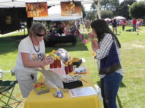 Theresa Callaway, left, representing her daughter Rebekah Hargraves&rsquo; business B&rsquo;s Bees of Loxley provides a sample for a festival goer at Saturday&rsquo;s Honeybee Festival.