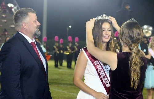 2016 RHS Homecoming Queen Ashley Taylor crowns senior Maddy Feller as the 2017 queen during halftime festivities of the Golden Bears&rsquo; contest against 6A Region 1 rival B.C. Rain Friday night as father Casey Feller looks on.