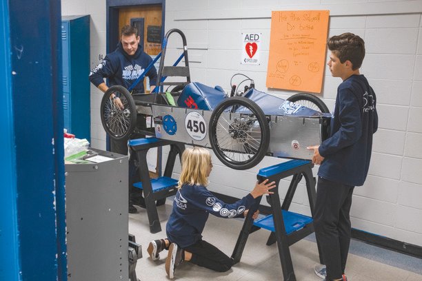 Caiden Bennett, Scott Prince and Tristyn Kutz prepare to work on Gulf Shores Middle School&rsquo;s Captain America stock racer for their GreenPower USA team.