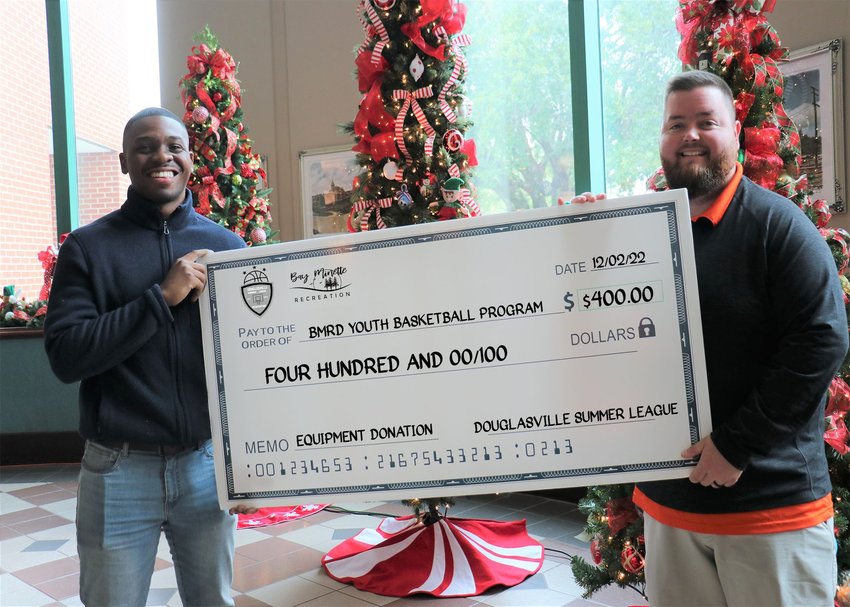Devante Smith presents a $400 donation check on behalf of the Douglasville Summer Basketball League to the Bay Minette Recreation Director Blake Clark Friday, Dec. 2. The department said the money will go toward ball lockers for the youth basketball program.