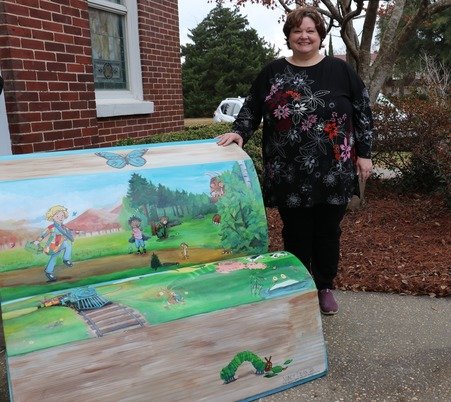 Nancy Dean stands with the bench she painted outside of Bay Minette Public Library.