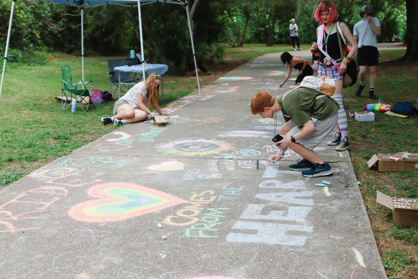 Attendees of Color Fairhope with Pride drawing on the sidewalk with chalk