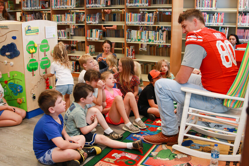 Trae Barry, a Summerdale native and member of the XFL North Champion D.C. Defenders, reads to a group of children at &ldquo;All Together Now,&rdquo; the kick-off event to Summerdale Public Library&rsquo;s annual summer reading program Tuesday, June 6.