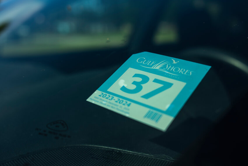 A Gulf Shores resident sticker is seen on the windshield of a car. In Gulf Shores, the decals allow residents free city parking as well as re-entry to the island after a storm. The number on the decal corresponds with the property's respective zone and allows police and emergency personnel to quickly identify who should be allowed into a restricted area(s) at the appropriate time.