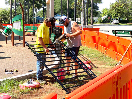 Workers install a black metal fence around Foley&rsquo;s Sara Thompson Kids Park on Monday, July 24. The fence replaces a temporary barrier in use while the park was under construction and since the facility opened May 27.