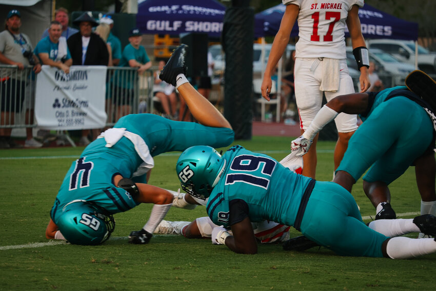 Gulf Shores&rsquo; Jordan Watson (19) and Carter Byrd (4) finish their pursuit of a St. Michael ballcarrier during the season-opening game between the Dolphins and Cardinals at Mickey Miller Blackwell Stadium Thursday night. The Dolphins went on to earn a 41-20 win.