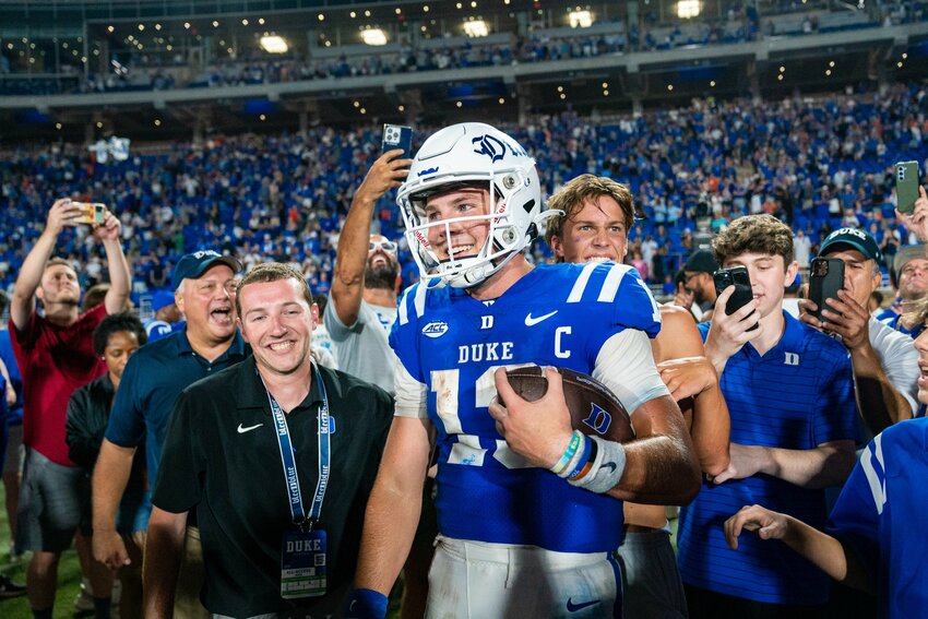 With his younger brother Devin right behind him, Riley Leonard takes in the scene on Brooks Field at Wallace Wade Stadium after Duke Blue Devil fans stormed the field following the 28-7 upset of No. 9 Clemson on Monday night. Leonard&rsquo;s 44-yard touchdown run gave Duke a 13-7 lead to open the second half and the Blue Devil defense complemented the effort with a second-half shutout.