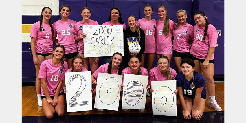 The Daphne Trojans celebrate the 2,000-assist milestone for senior setter Lucy McCoy in their home gym on Wednesday, Oct. 11, following a 2-1 win over the eighth-ranked Hoover Bucs. McCoy was gifted a commemorative volleyball to mark the occasion just over a year after she hit the millennium mark.