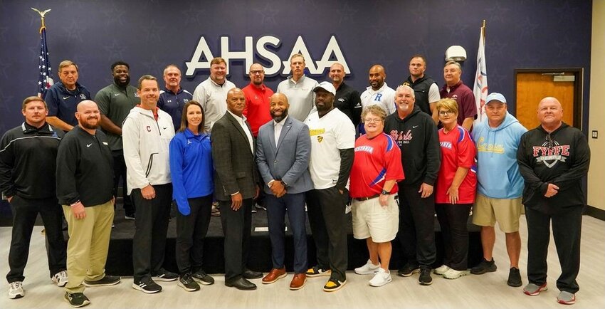 The Super 7 head coaches gathered at the AHSAA Office on Saturday, Dec. 2, for the final meeting of the postseason ahead of next week&rsquo;s state championships. Pictured in the front row, from the left, are Matt Johnson, Reeltown (2A); Chan Lowe, Leroy (1A); Mitchell Holt, Central-Phenix City Girls&rsquo; Flag (6A/7A); Whitney Toole, Montgomery Catholic Girls&rsquo; Flag (1A/5A); AHSAA Executive Director Alvin Briggs; AHSADCA Director Brandon Dean; Cedric Lane, Wenonah Girls&rsquo; Flag (1A/5A); Debra Broome, Doug Rogers, and Sharman Martin, Vestavia Hills Girls&rsquo; Flag (6A/7A); Mark O&rsquo;Bryant, Coosa Christian (1A); and Paul Benefield, Fyffe (2A). Pictured in the back roe, from the left, are Ronnie Cottrell, Mobile Christian (3A); Kirk Johnson, Montgomery Catholic (4A); Mark Hudspeth, Gulf Shores (5A); Jeff Kelly, Saraland (6A); Central-Phenix City AD Mark Bell representing head coach Patrick Nix (7A); Mark Freeman, Thompson (7A); Drew Gilmer, Clay-Chalkville (6A); Ronnie Jackson, Ramsay (5A); Jacob Kelley, Cherokee County (4A); and Bob Godsey, Madison Academy (3A).