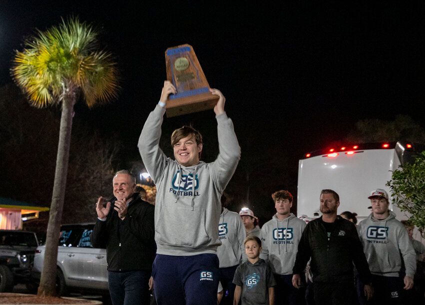 Gulf Shores junior Chase Jennings hoists the Blue Map trophy as the Dolphins arrive at Lulu&rsquo;s for the championship celebration on Wednesday, Dec. 13. The football team was recognized for winning its first state championship in program history.