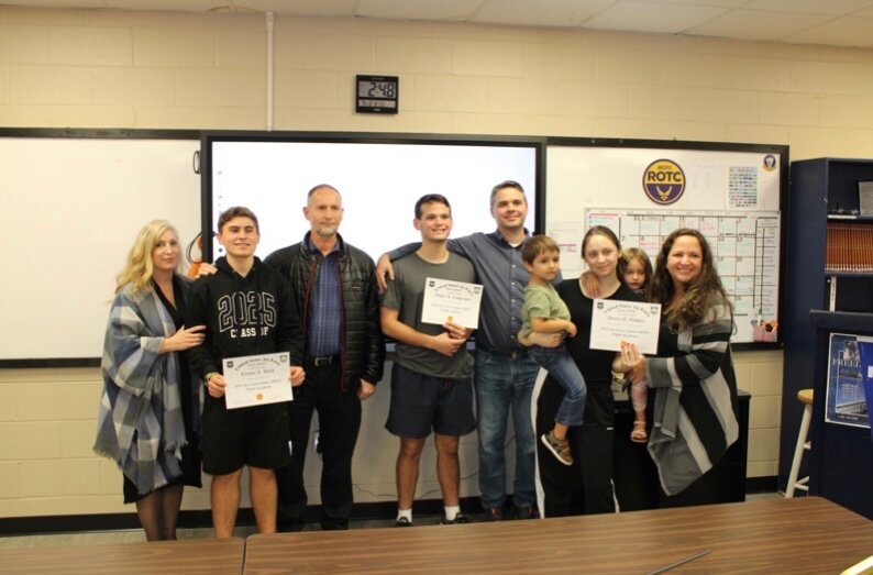 Cadets Landon Ward, Arthur Zamprogno and Grace Godwin pose with their families holding their certificates for a scholarship to attend an accredited private pilot license training program for the summer of 2024.