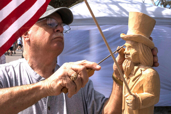 MICAH GREEN / GULF COAST MEDIA..Chip Smith, of Fairhope, works on a wood carving during Ballyhoo Festival at Gulf State Park on Saturday. .