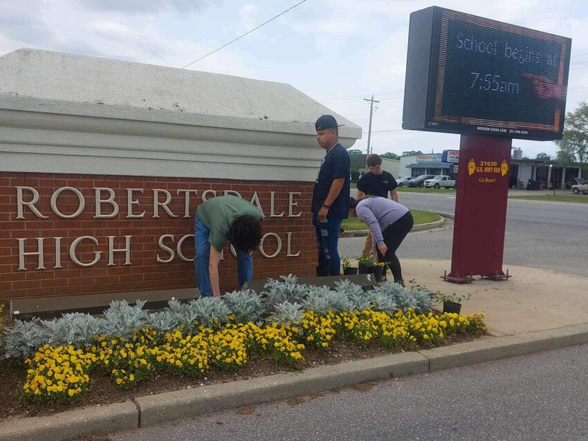Mr. Merritt&rsquo;s class plants flowers at the school's sign during a campus beautification project April 8.