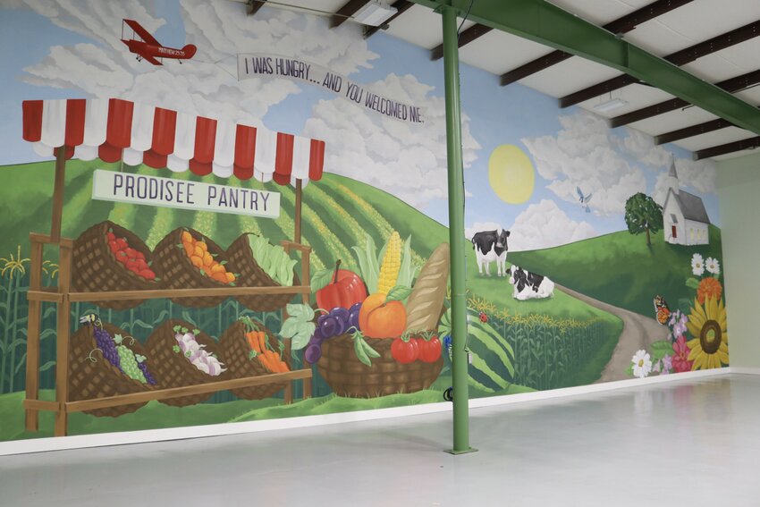 The full wall mural features several small details that highlight aspects of the Prodisee Pantry from the baskets full of produce to the lights being on in the church building.