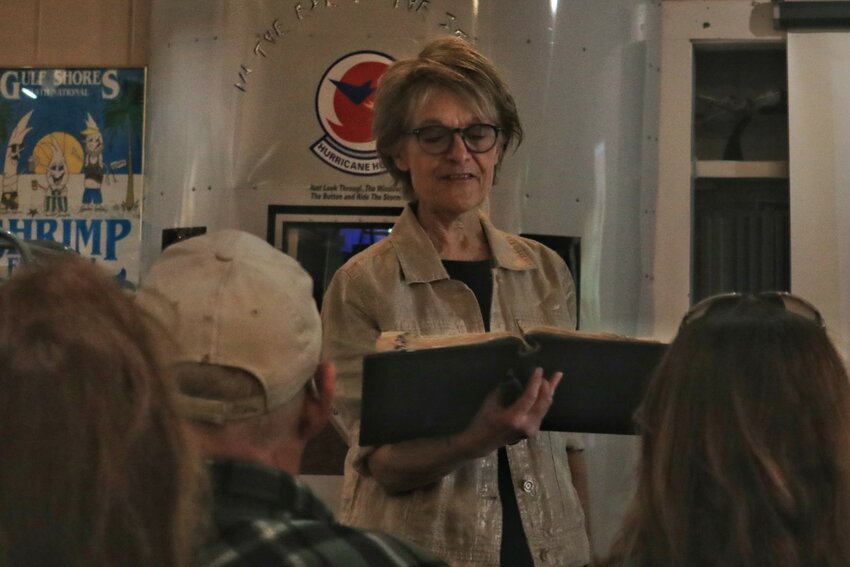 Dolores Hydock shows the length of hair Louisa May Alcott cut when she had typhoid fever by using a measuring tape and a participating audience member.