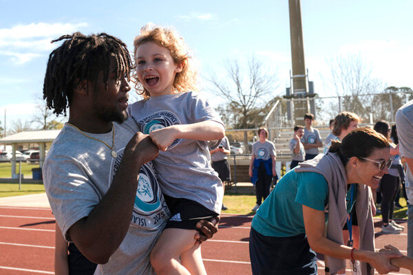 Gulf Shores High School student Janoy Ferguson fist bumps with Gulf Shores 1st grader August Riddle after Riddle competed in the 50-meter dash.