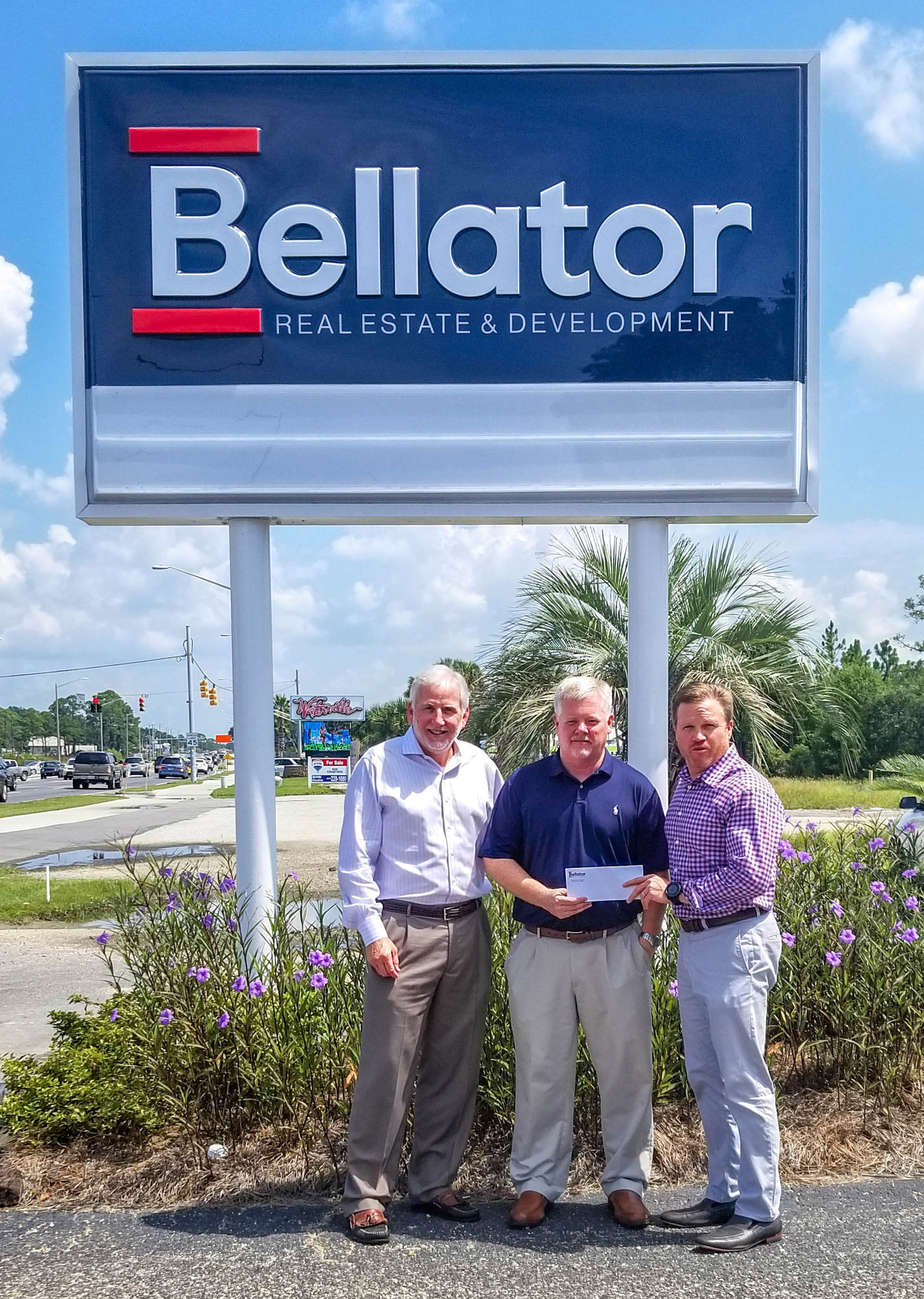 Bellator Real Estate & Development acquires Triple Option Properties: From left, Bellator Gulf Shores Managing Broker Frank Malone, REALTOR® Brad Chambers, formerly of Triple Option Properties, and Bellator President Troy Wilson stand in front of the Gulf Shore’s office sign.