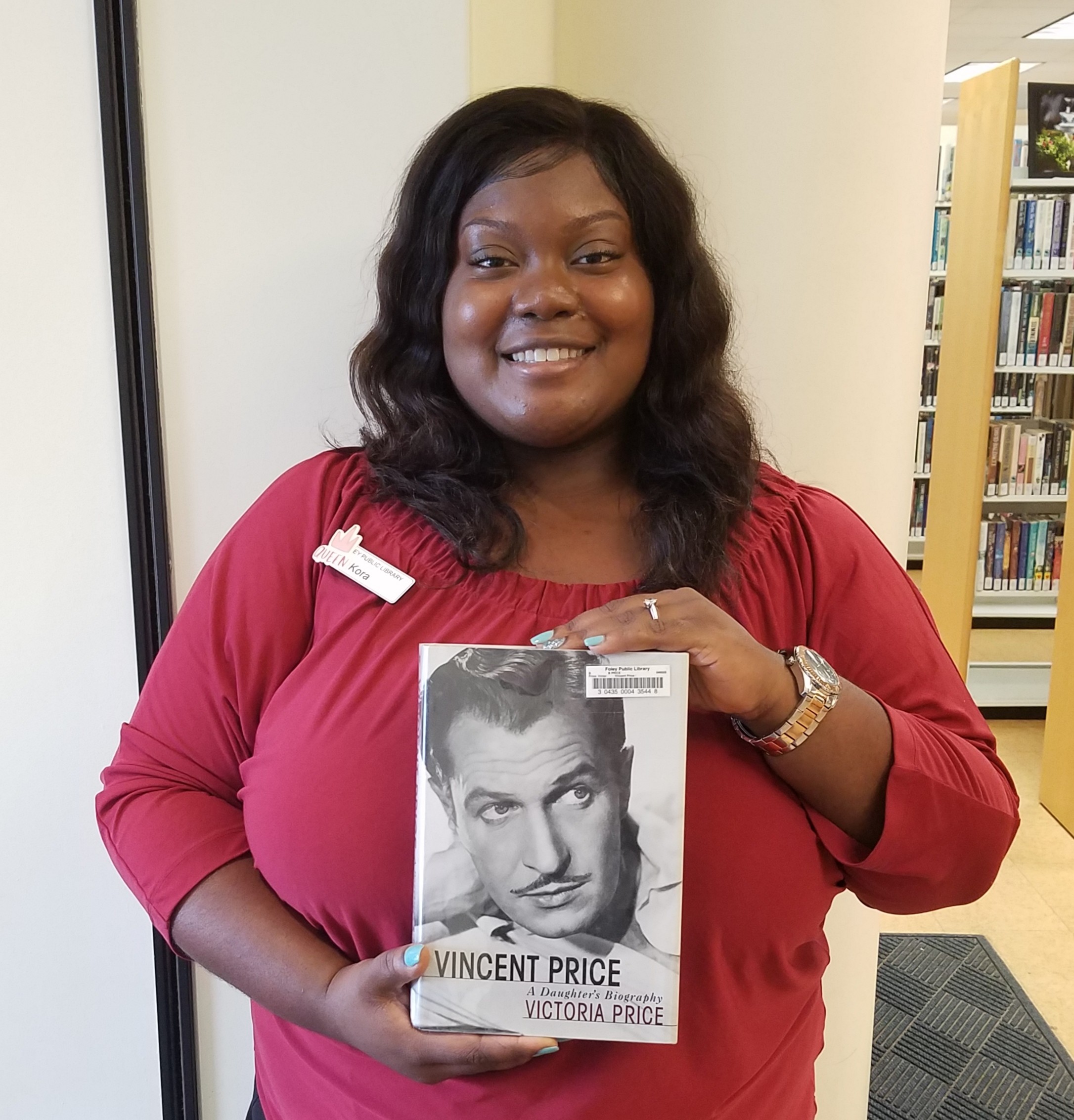 Library Aide, Kora Benford, holding a Vincent Price biography available at the Foley Public Library.