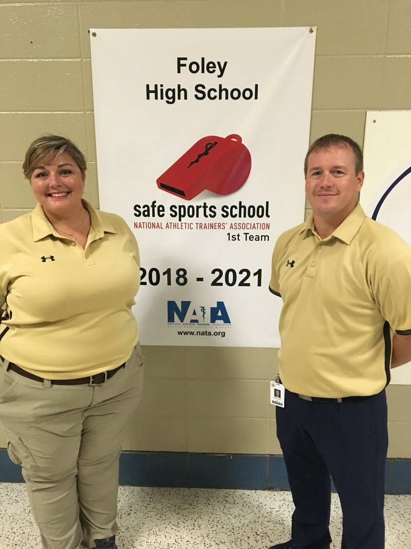 Athletic Trainer Kristina Estis and Athletic Trainer Sean Ahonen in front of FHS’s Sports Safety Award banner.