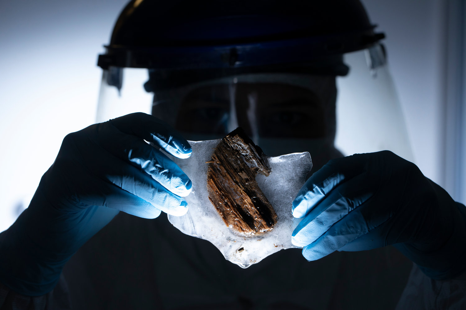 A researcher holds a piece of wood encased in ice taken from the interior hull of the wreck of the Clotilda.